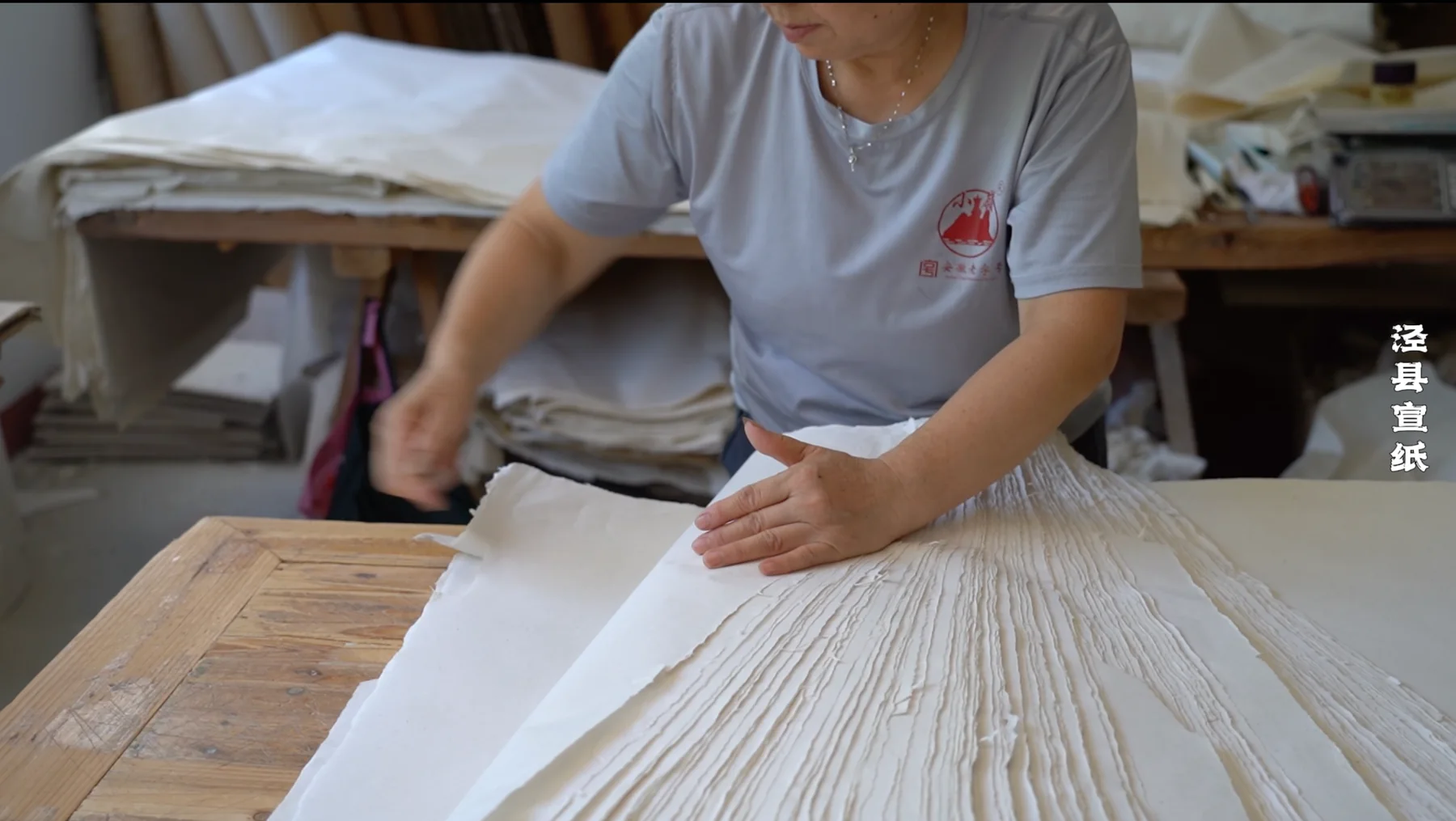Craftsperson handling stacks of handmade Xuan paper